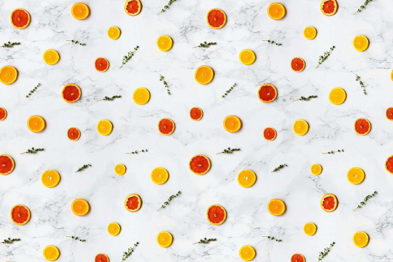 Colorful citrus slices arranged in a flat lay pattern on a marble surface, ideal for backgrounds.