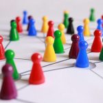 A strategic arrangement of colorful pawns connected on a game board, symbolizing networking and teamwork.